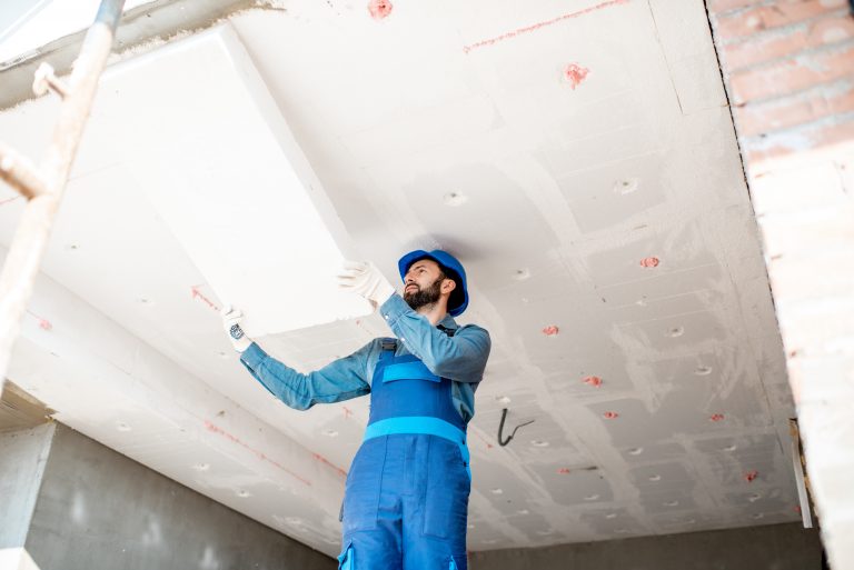 worker on scaffolding installing ceiling